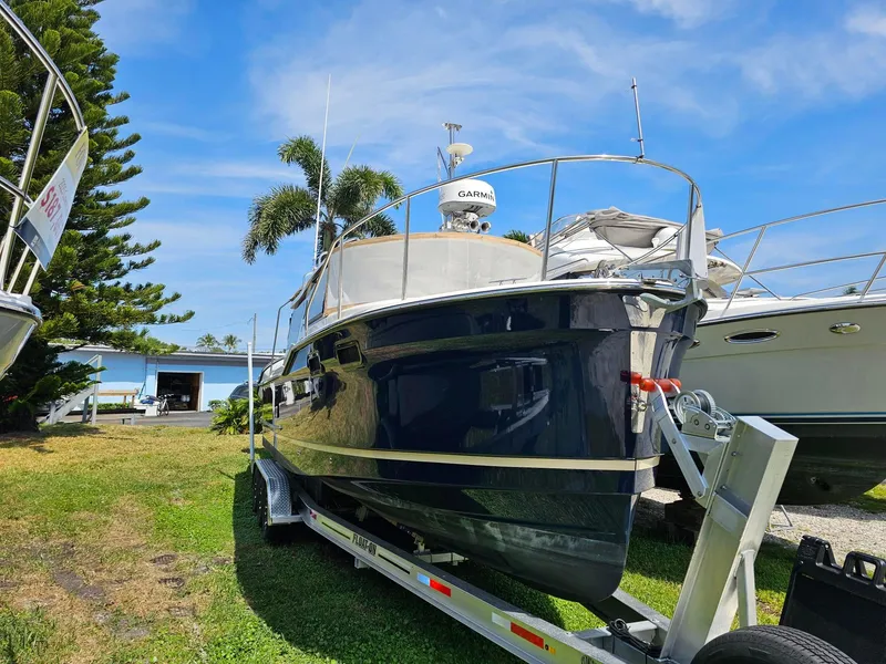 Slide: The Image of 2023 Ranger Tugs 27R boat on trailer, parked outdoors under a clear blue sky. - 2