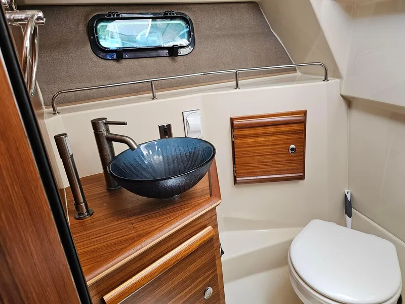 Slide: The Image of 2023 Ranger Tugs 27R bathroom with modern sink, wooden cabinetry, and compact design. - 20
