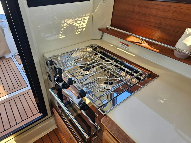 Slide: The Image of 2023 Ranger Tugs 27R interior kitchen with stove and wooden accents. - 22