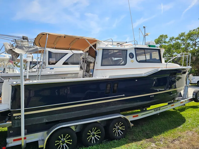 Slide: The Image of 2023 Ranger Tugs 27R boat on trailer, parked outdoors under clear sky. - 6