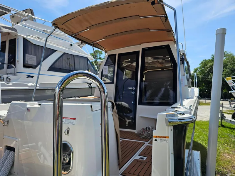 Slide: The Image of 2023 Ranger Tugs 27R boat with canopy, docked outdoors on a sunny day. - 7
