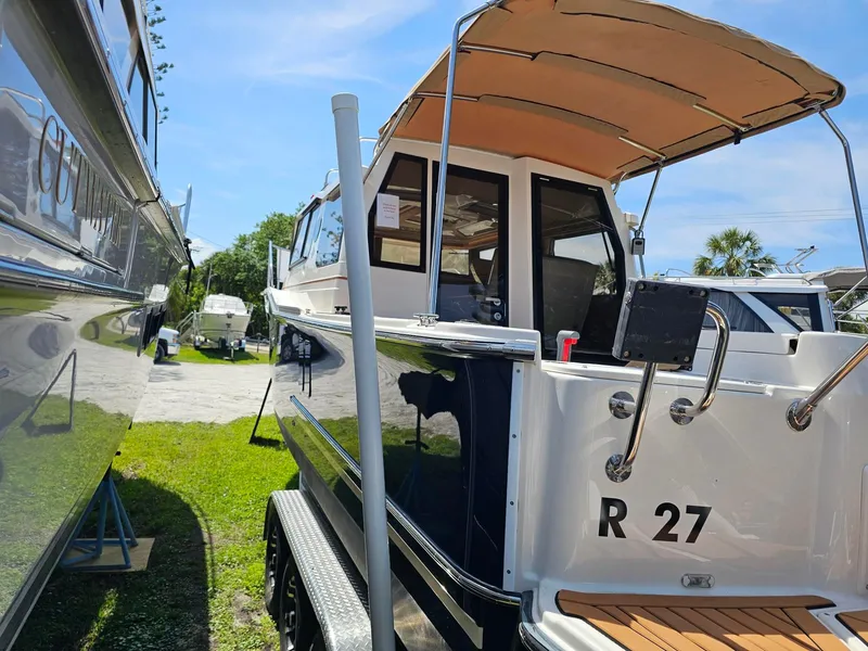Slide: The Image of 2023 Ranger Tugs 27R boat with canopy, docked outdoors on a sunny day. - 8