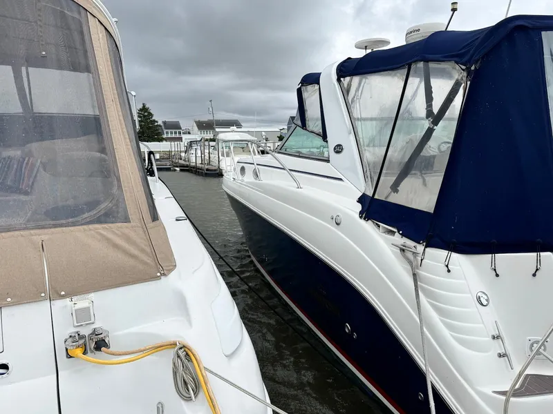 The Image of 2006 Rinker 342 Express Cruiser docked beside another boat under cloudy skies. - 0