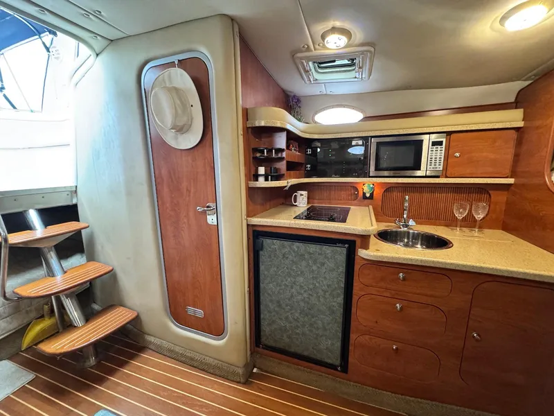 Slide: The Image of 2006 Rinker 342 Express Cruiser interior with kitchenette, featuring wood cabinetry and modern appliances. - 13