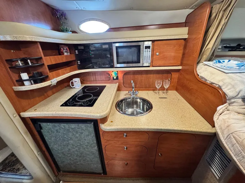 Slide: The Image of 2006 Rinker 342 Express Cruiser kitchen with stove, sink, microwave, and storage cabinets. - 14