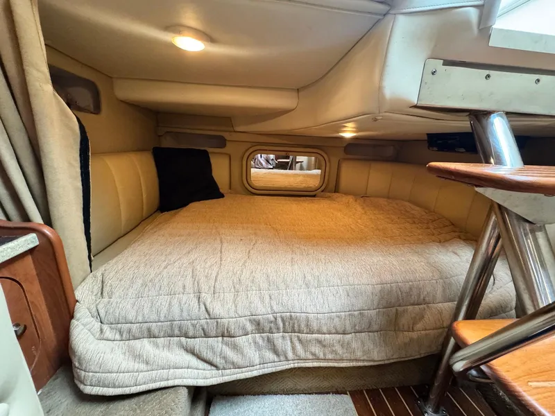 Slide: The Image of 2006 Rinker 342 Express Cruiser cabin interior with cozy bed and wooden accents. - 17