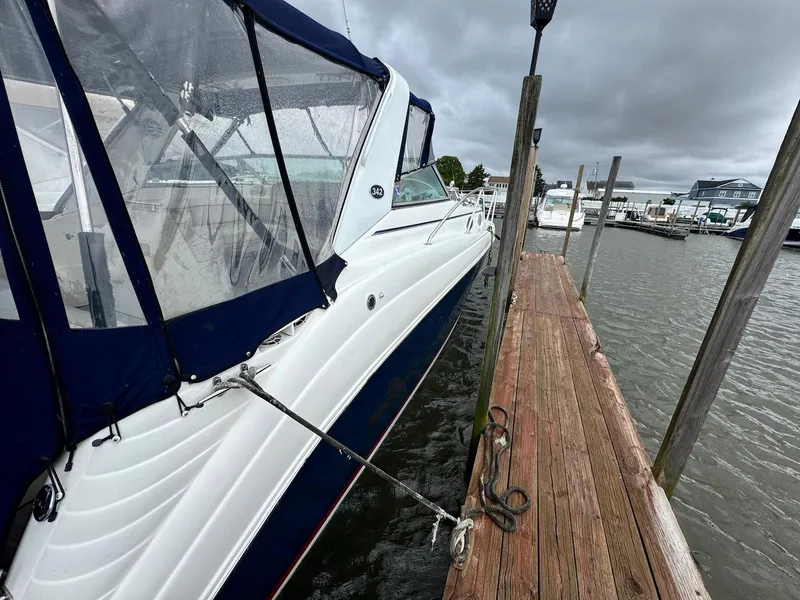 Slide: The Image of 2006 Rinker 342 Express Cruiser docked at marina under cloudy skies. - 2