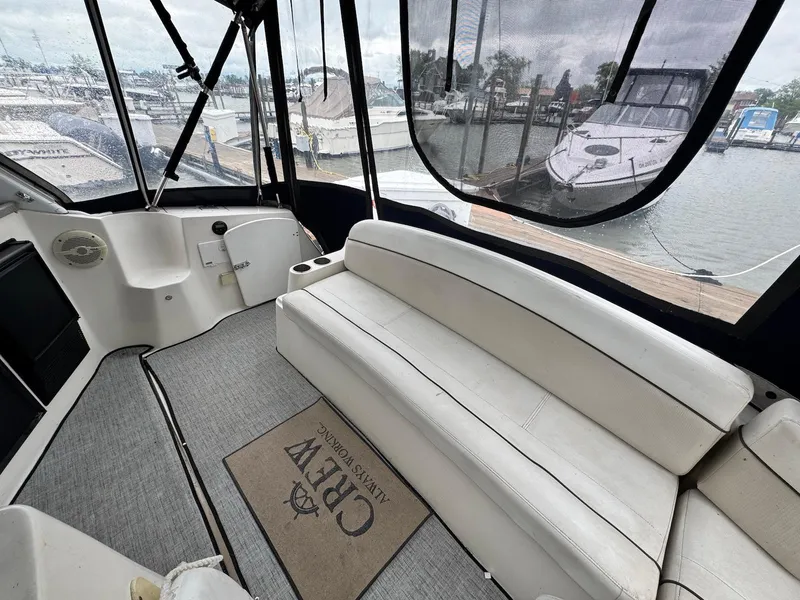 Slide: The Image of 2006 Rinker 342 Express Cruiser interior with white seating and marina view. - 4