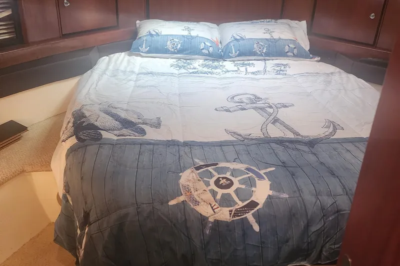 Slide: The Image of Cozy bedroom in 1999 Trojan 440 Express Yacht with nautical-themed bedding. - 6