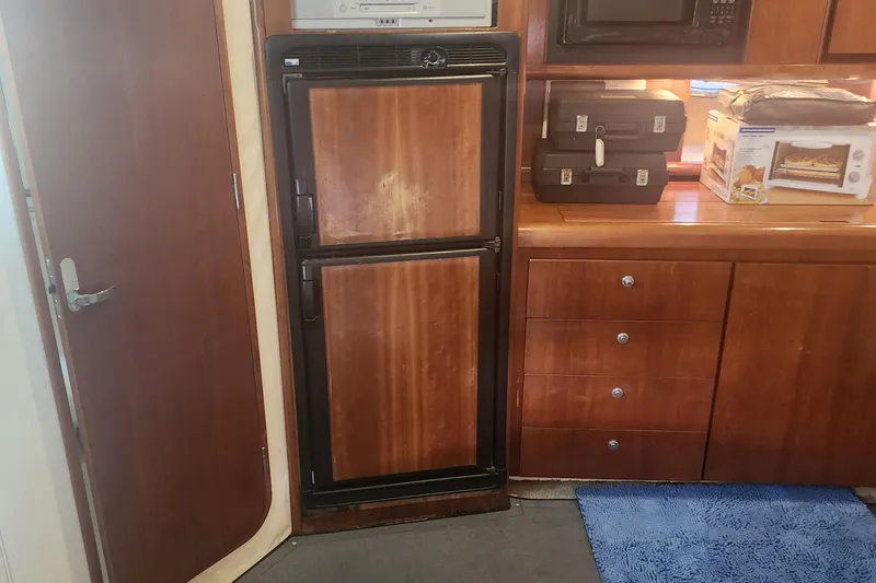 Slide: The Image of Interior of 1999 Trojan 440 Express Yacht with wooden cabinetry and compact appliances. - 5