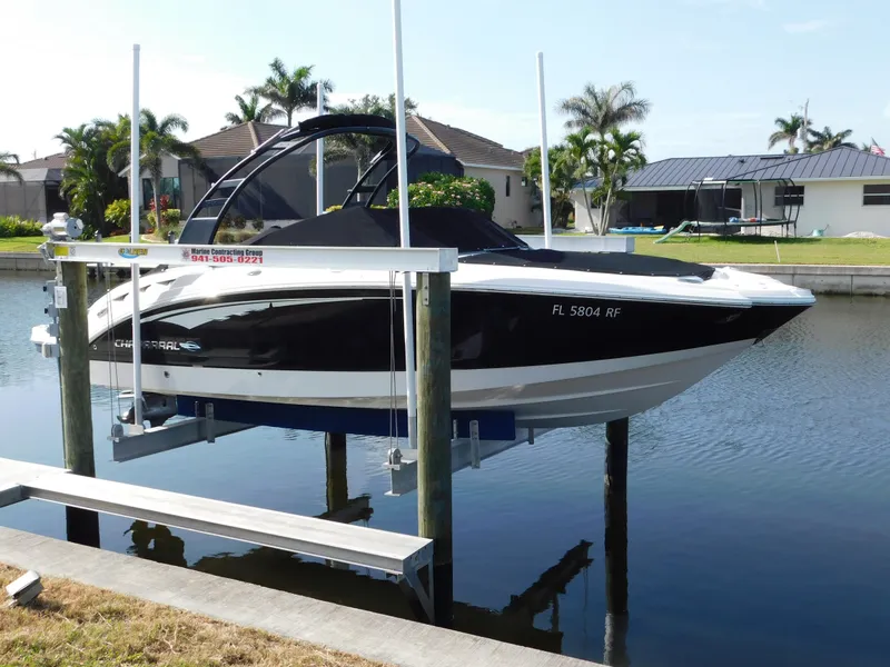 Slide: The Image of 2017 Chaparral 244 Sunesta boat on lift, docked in a canal with palm trees. - 0