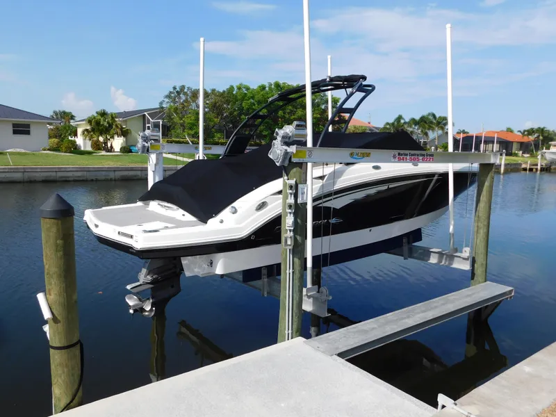 Slide: The Image of 2017 Chaparral 244 Sunesta boat on lift at dockside, calm water background. - 3