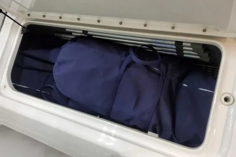 Slide: The Image of Storage compartment in a 2027 Formula 290 Bowrider, containing blue bags and poles. - 25