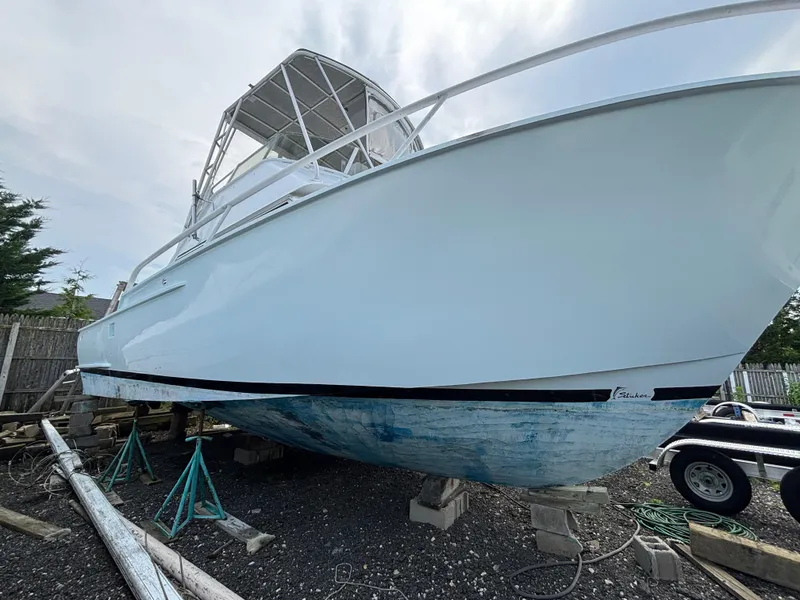 Slide: The Image of 1974 Striker Canyon Runner boat on stands, white hull, outdoor setting. - 6