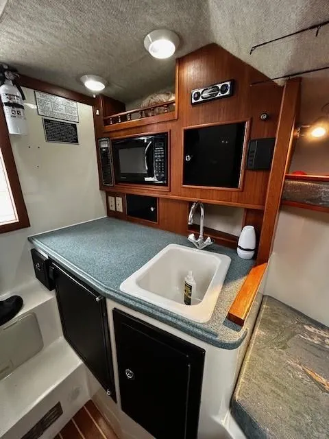 Slide: The Image of 2005 Carolina Classic 28 Express cabin with kitchenette, sink, and microwave. - 24