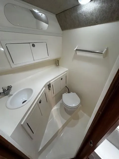 Slide: The Image of 2005 Carolina Classic 28 Express boat bathroom with sink, toilet, and storage cabinets. - 25