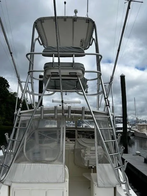 Slide: The Image of 2005 Carolina Classic 28 Express boat with tower, docked at marina under cloudy sky. - 4