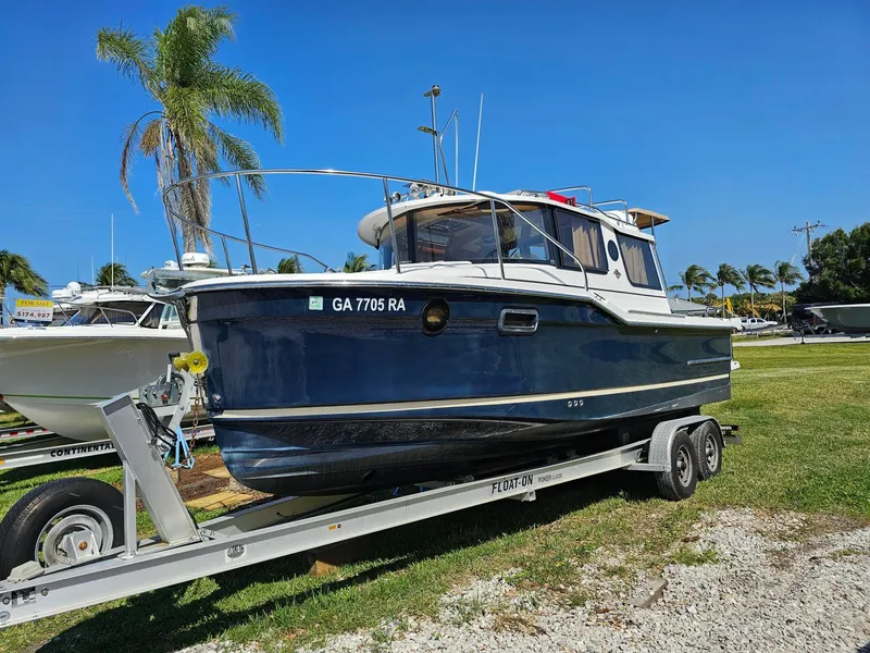 Slide: The Image of 2019 Ranger Tugs 23R boat on trailer, parked outdoors under clear blue sky. - 13
