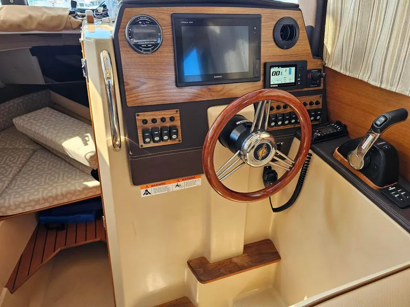Slide: The Image of 2019 Ranger Tugs 23R helm with wooden steering wheel and modern navigation controls. - 15