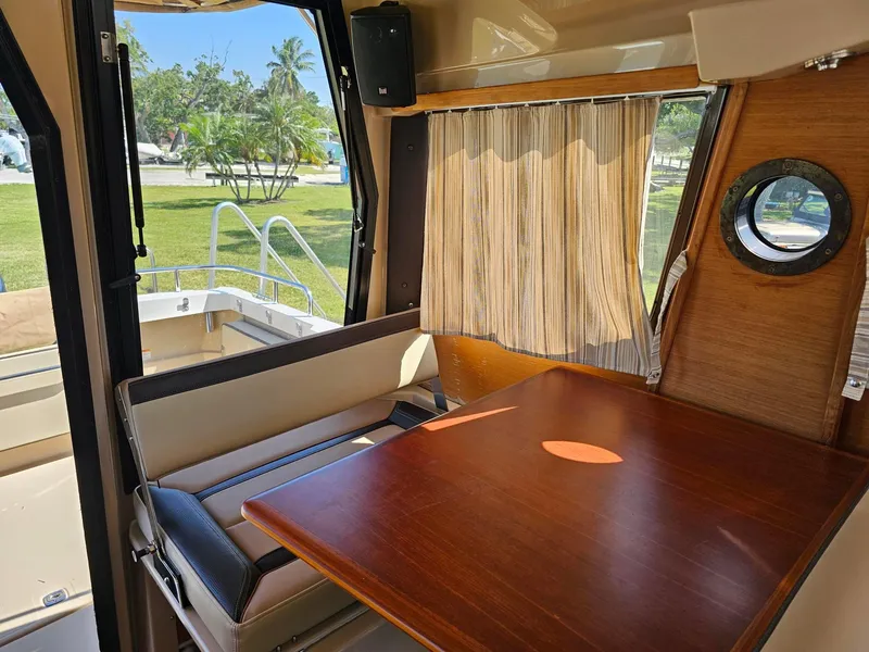 Slide: The Image of Interior of 2019 Ranger Tugs 23R with wooden table and seating, window view. - 21