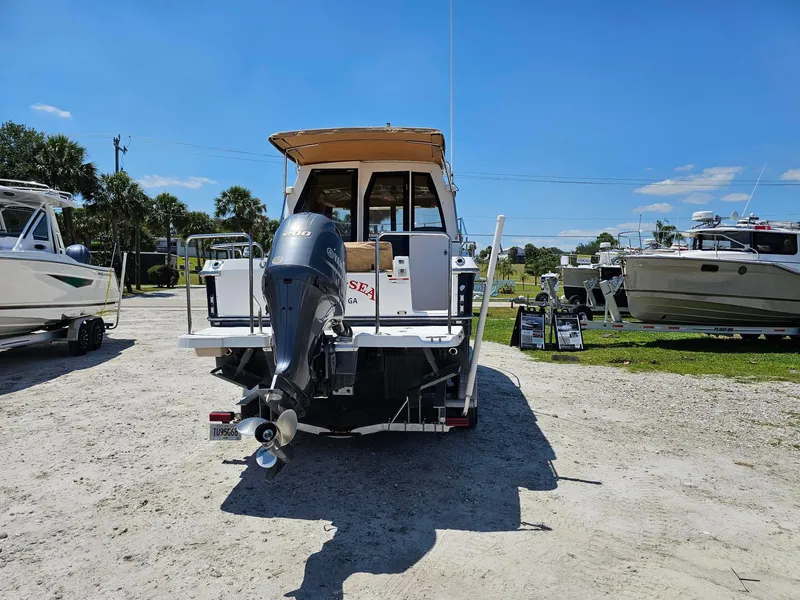 Slide: The Image of 2019 Ranger Tugs 23R boat with outboard motor, parked on gravel under clear blue sky. - 4