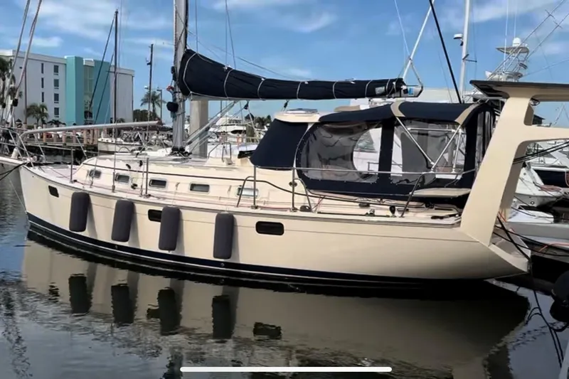 The Image of 2021 Island Packet 349 sailboat docked in marina, featuring beige hull and black canvas covers. - 0