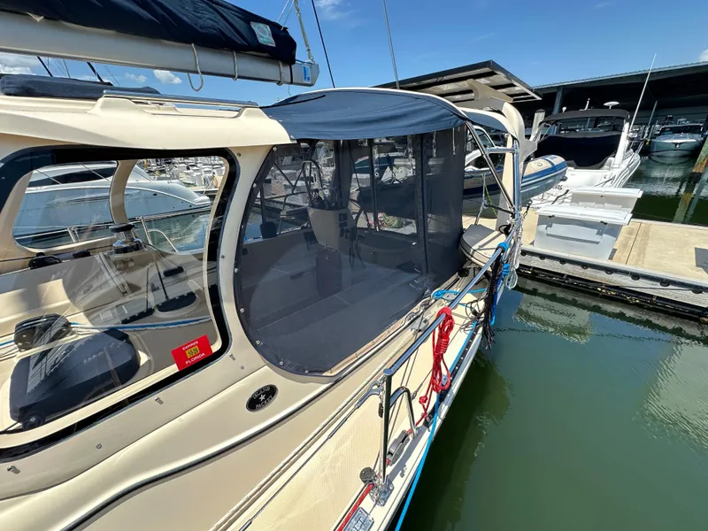 Slide: The Image of 2021 Island Packet 349 sailboat docked, featuring a covered cockpit and marina backdrop. - 14