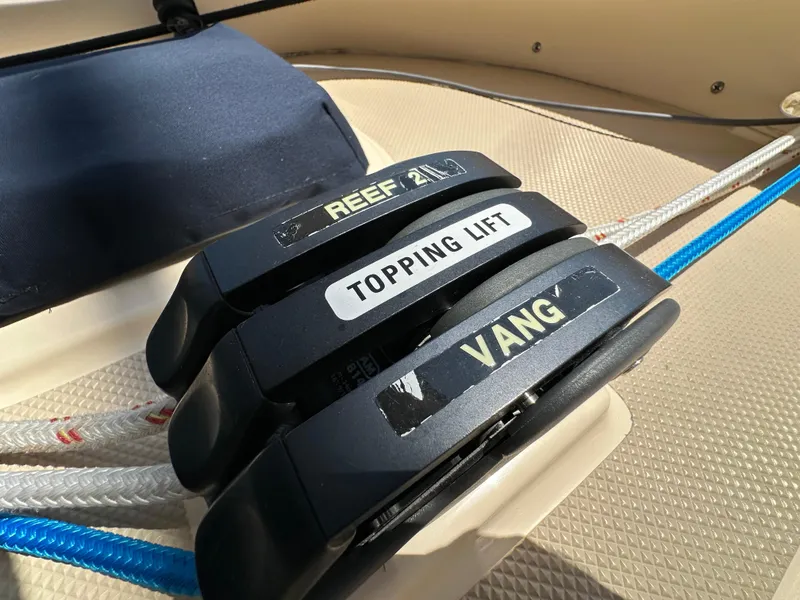 Slide: The Image of Close-up of sailing rope clutches labeled "Reef 2," "Topping Lift," and "Vang" on Island Packet 349. - 26