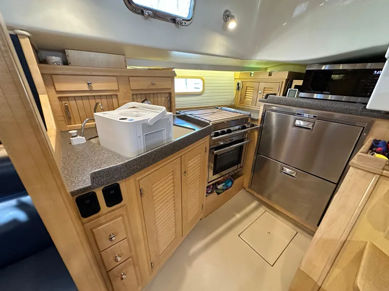 Slide: The Image of 2021 Island Packet 349 yacht interior kitchen with modern appliances and wooden cabinetry. - 31