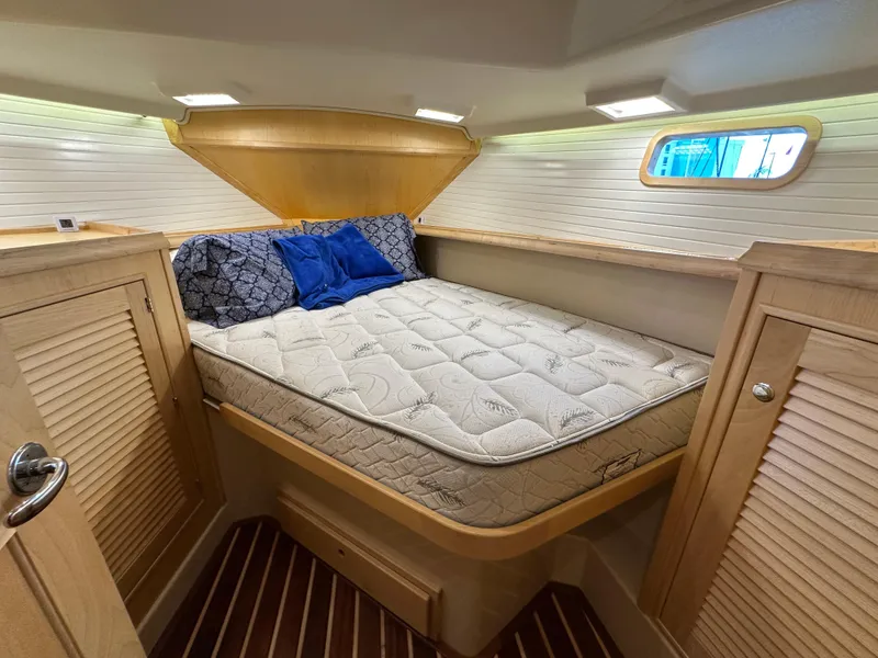 Slide: The Image of 2021 Island Packet 349 cabin interior with cozy bed and wooden cabinetry. - 40