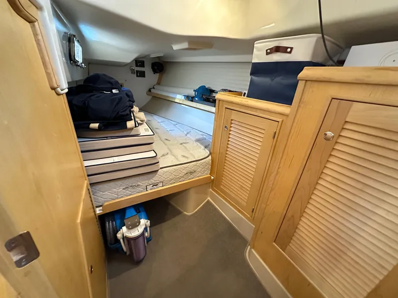 Slide: The Image of 2021 Island Packet 349 cabin interior with bed, storage cabinets, and nautical equipment. - 49
