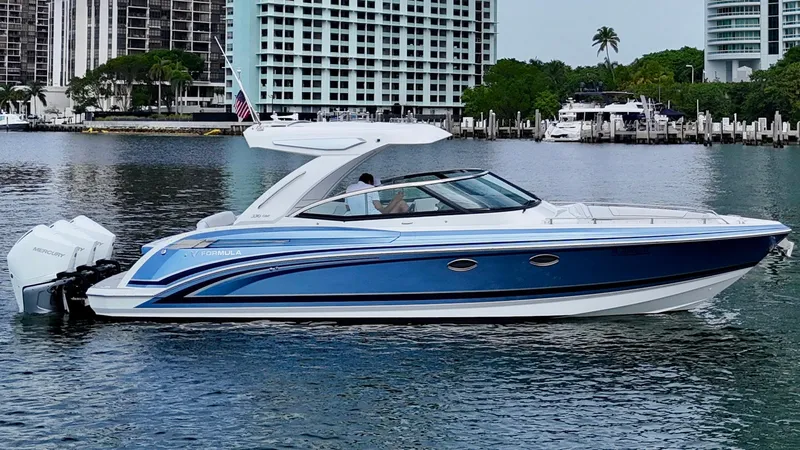 Slide: The Image of 2023 Formula 330 Crossover Bowrider OB on water, sleek blue design, modern architecture. - 1