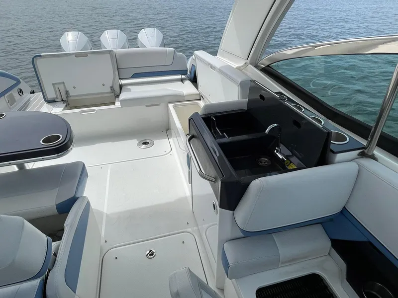 Slide: The Image of 2023 Formula 330 Crossover Bowrider OB interior with seating and kitchenette, on calm water. - 28