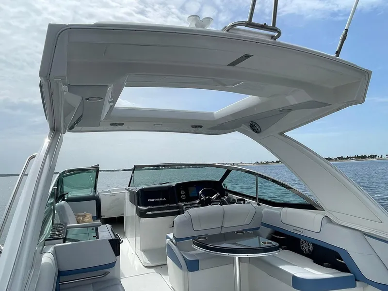 Slide: The Image of 2023 Formula 330 Crossover Bowrider OB on water, showcasing luxurious interior and helm. - 33