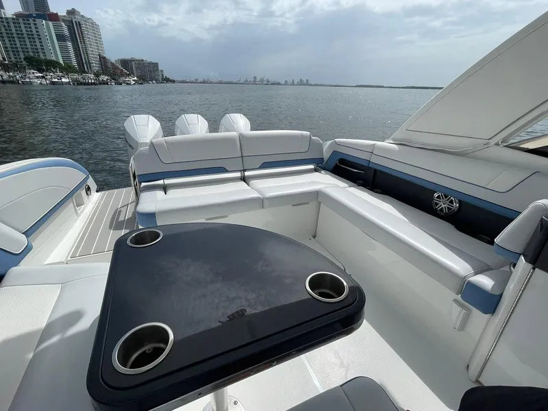 Slide: The Image of 2023 Formula 330 Crossover Bowrider OB interior with seating and table, overlooking waterfront. - 35