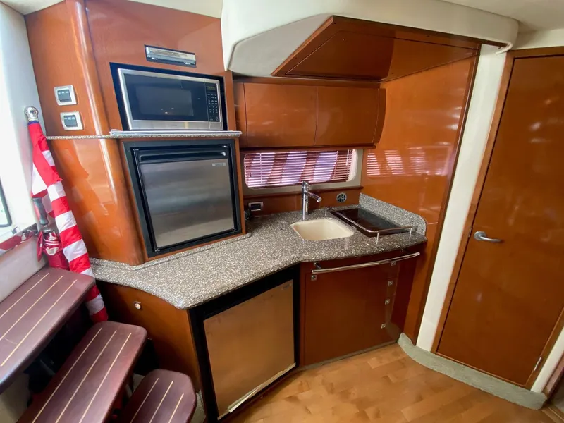 Slide: The Image of 2008 Sea Ray 38 Sundancer galley with microwave, sink, and wood cabinetry. - 14