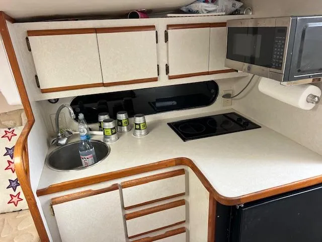 Slide: The Image of 1997 Blackfin 30.7 EXPRESS boat kitchen with sink, stove, microwave, and storage cabinets. - 21