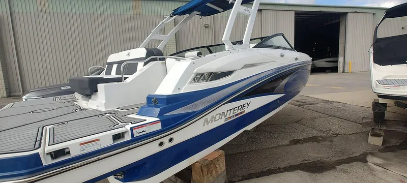 Slide: The Image of 2021 Monterey M4 boat in blue and white, docked near a warehouse. - 2