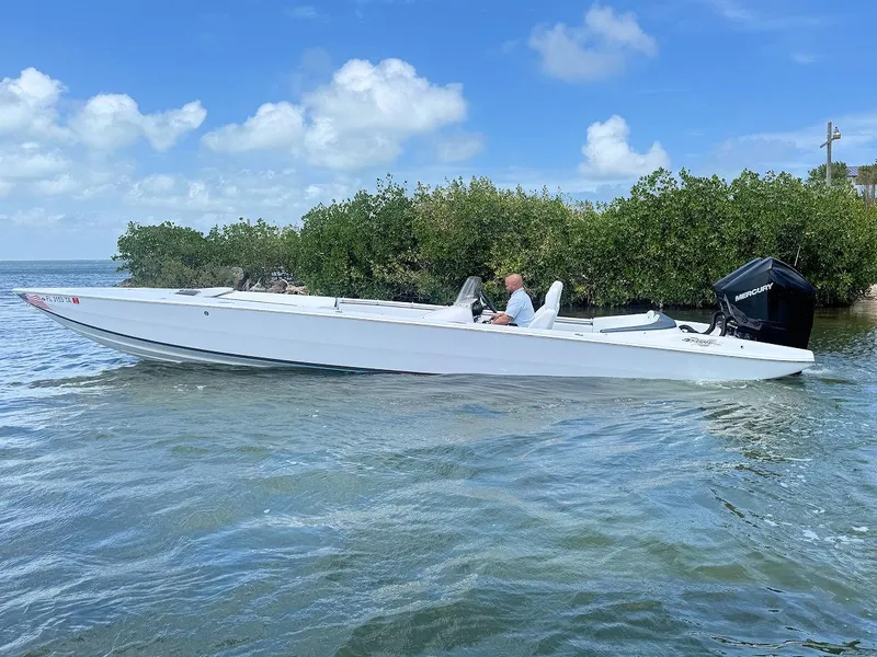 Slide: The Image of 2022 Phantom 32 CC boat on water, surrounded by lush greenery and blue sky. - 2