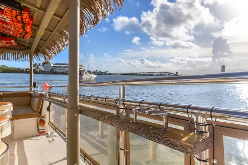 Slide: The Image of Tropical-themed Beachcat 26 Tiki COI boat on serene water with bridge and cloudy sky. - 13