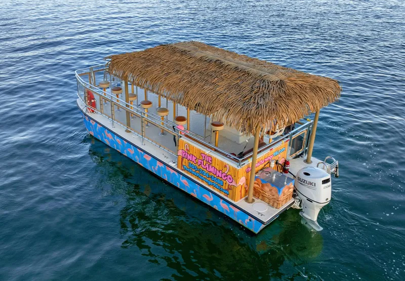Slide: The Image of 2023 Beachcat 26 Tiki COI boat with thatched roof on water. - 15