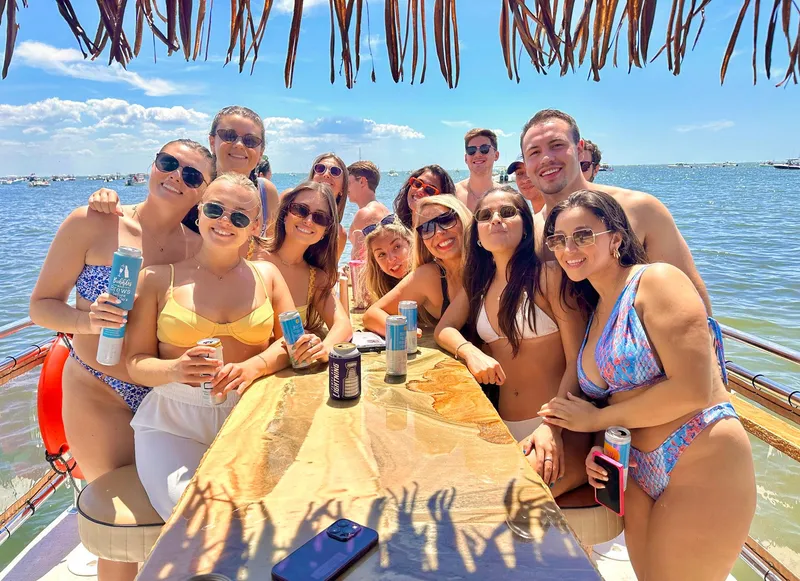 Slide: The Image of Group enjoying sunny day on 2023 Beachcat 26 Tiki COI boat, holding drinks. - 27