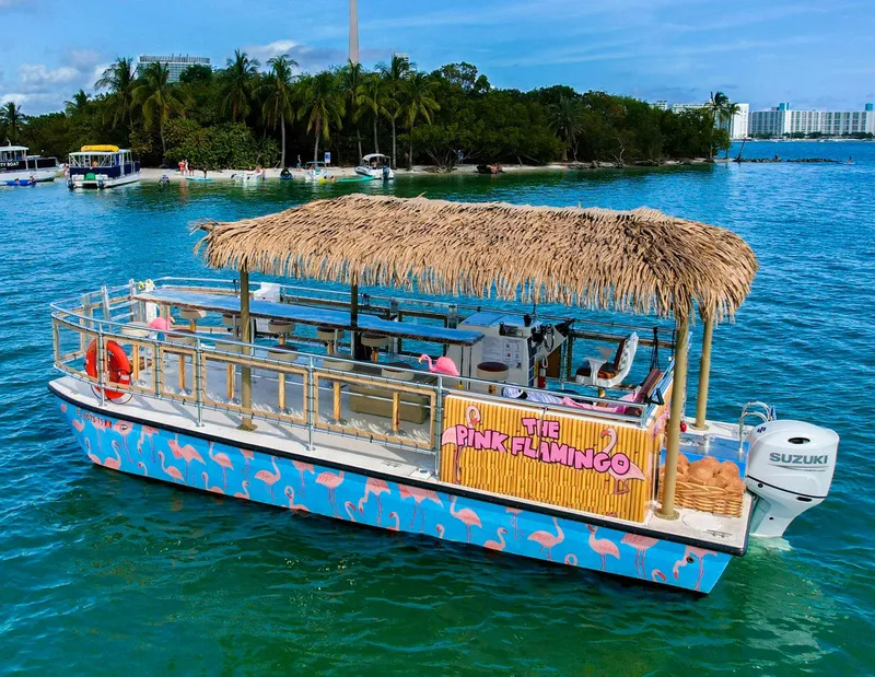 Slide: The Image of Tropical-themed 2023 Beachcat 26 Tiki COI boat on blue water with palm trees in background. - 3