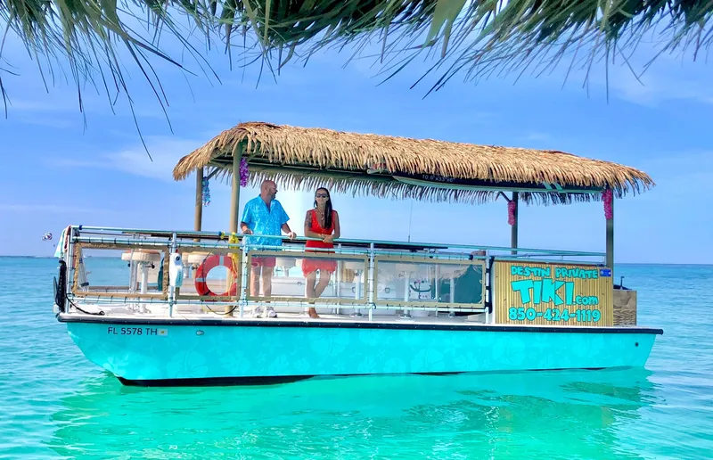 Slide: The Image of 2023 Beachcat 26 Tiki COI boat on turquoise water with thatched roof and passengers. - 30