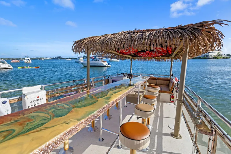 Slide: The Image of 2023 Beachcat 26 Tiki COI boat with bar seating and straw canopy on the water. - 6