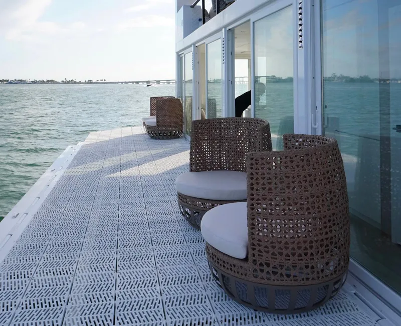 Slide: The Image of Floating deck of Arkup 50 houseboat with wicker chairs, overlooking serene waters. - 14