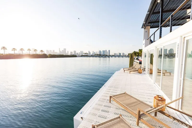 Slide: The Image of Modern Arkup 50 houseboat with solar panels, overlooking serene water and city skyline, 2025 model. - 15