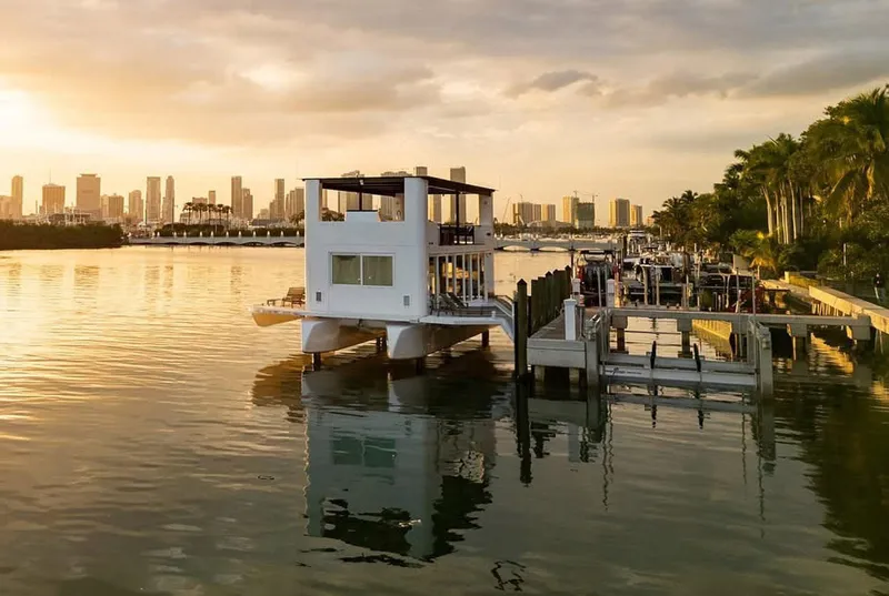 Slide: The Image of Floating modern houseboat, Arkup 50, docked at sunset with city skyline in background. - 21