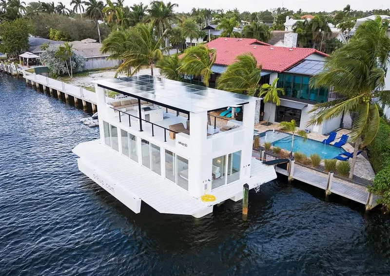 Slide: The Image of Modern Arkup 50 houseboat docked by waterfront homes, surrounded by palm trees. - 3