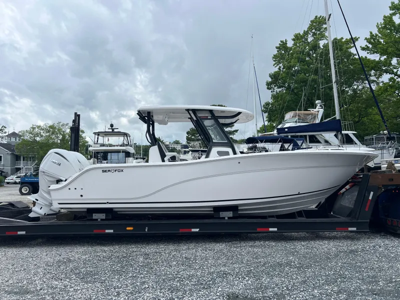 The Image of 2025 Sea Fox 288 Commander boat on trailer, parked outdoors under cloudy sky. - 0